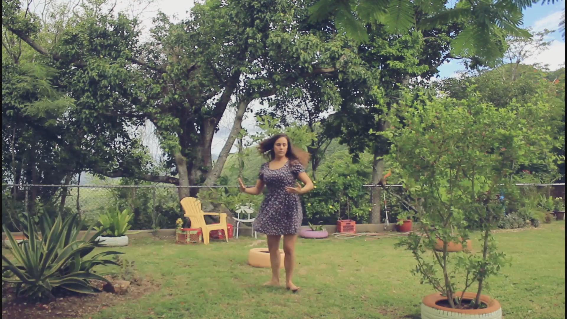 Load video: woman in a floral dress twirling in her backyard