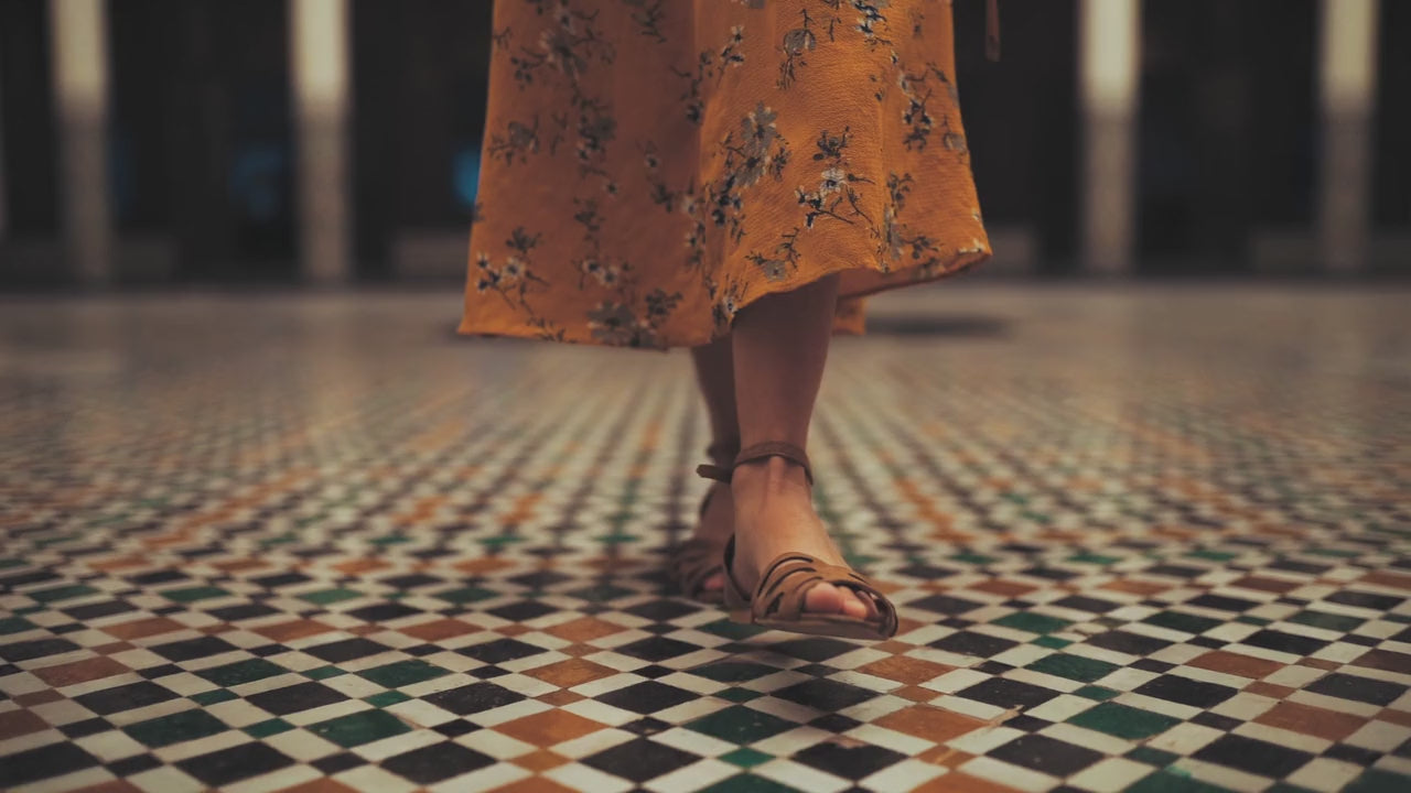 Load video: woman walking in sandals on a marble floor